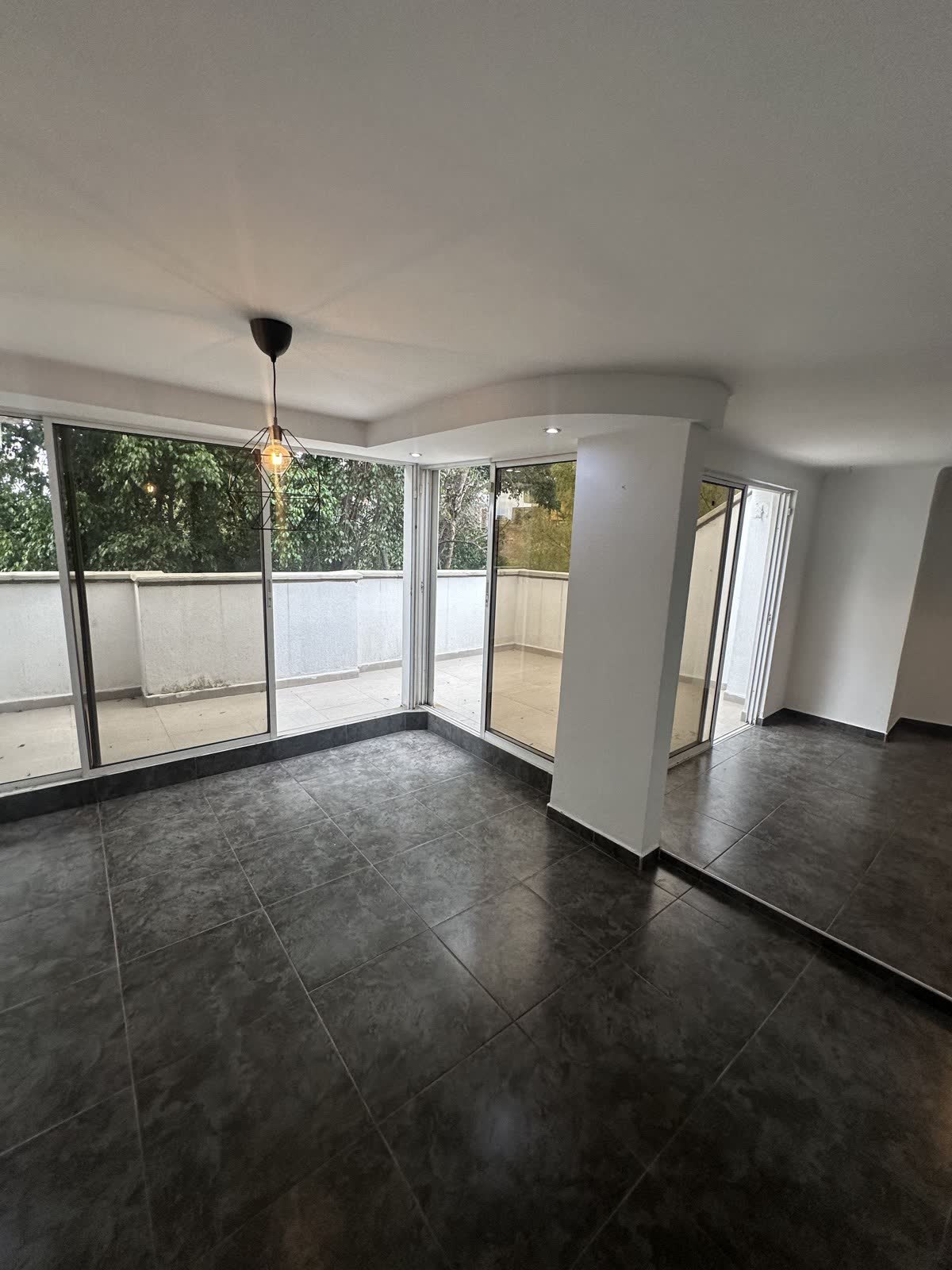 Sala del apartamento con ventanales esquineros y salida a la terraza